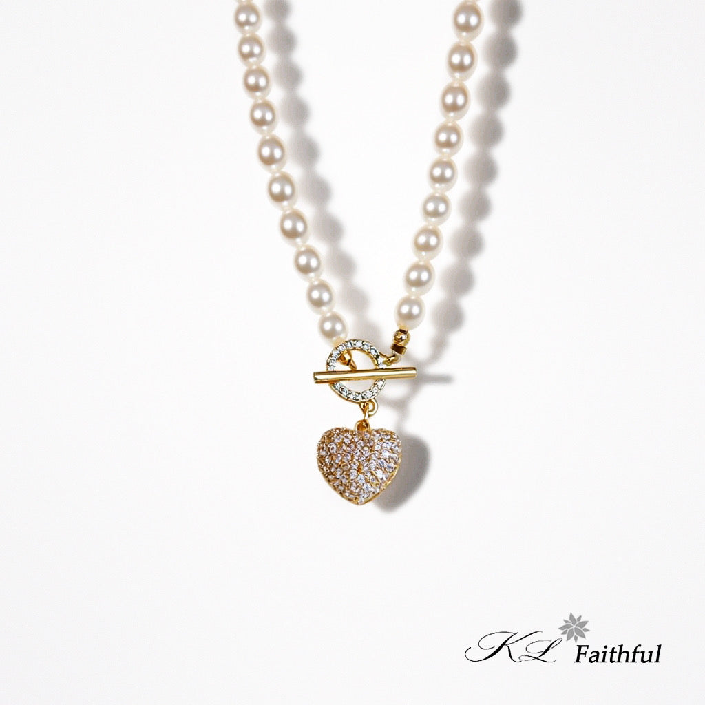 Gold pearl necklace with heart pendant on white background